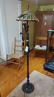Full view of vintage wood floor lamp with Tiffany style stained glass shade and pull chains for operation.