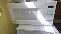 White Emerson microwave oven on a surface, front and control panel visible.