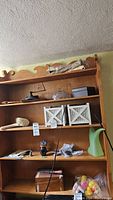Photo of wooden shelving unit displaying items including Murano glass bottle, rubber ducks, knobs/buttons, box, antique coffee grinder, planters, and others.