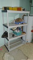 Side view of plastic shelving unit with various items on shelves, taken in basement near water heater.
