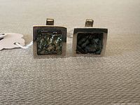Front view of the pair of Taxco sterling silver cufflinks with square abalone shell inlay, showing texture and color.