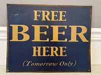 Full view of the rectangular metal sign with yellow text on dark blue background showing 'FREE BEER HERE (Tomorrow Only)'