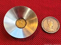 Photo showing both metal bowl with embedded bronze coin and separate bronze medal with female profile