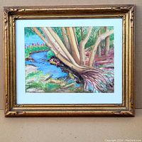 Framed watercolour painting showing tree trunks and roots by a stream, in an aged gold frame with white matting