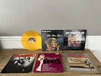 Top view of five vinyl albums on a wooden surface, one yellow translucent vinyl record visible.