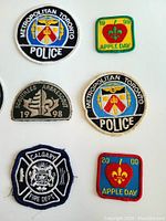 Close up of four badges including two Metropolitan Toronto Police patches, Scout patch, and Calgary Fire Department badge with clear details of embroidery and colors.