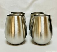 Front angled view of four stainless steel wine glasses showing their smooth brushed exterior surface and stemless rounded bowl design.