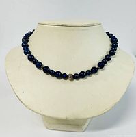 Full necklace displayed on a necklace bust showing dark blue beads with one sterling silver accent bead in the center.