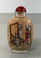 Front view of the glass perfume bottle featuring the detailed erotic painting of two figures inside a room.
