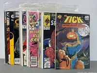 Front view of 12 comic books in protective sleeves showing The Tick, Iron Man, and Spider-Man among others