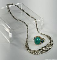 Rhinestone necklace and filigree ring shown on clear display stand to capture overall look and pairing.