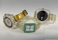 Three lucite watches including two Lucerne watches and one Swatch displayed on white surface