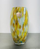 Front view of oval glass vase showing colorful Murano style mottled pattern and label.