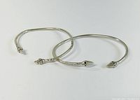 Two sterling silver cuff bracelets with snake motifs, one placed partially overlapping the other on a white background