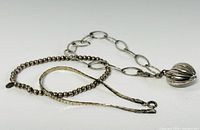 Three sterling silver bracelets including a chain link with heart charm, stretch bead bracelet and flat chain bracelet.