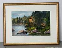 Frontal view of framed watercolor painting showing gold-tone frame, white mat, and landscape scene