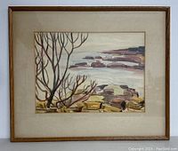 Framed watercolour painting matted and showing landscape with rocks and bare trees.
