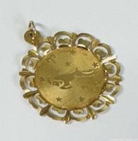 Front view of the yellow gold pendant showing engraved ram zodiac sign with scalloped openwork border and stars.