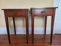 Front view showing both tables side by side on plank flooring against painted wall