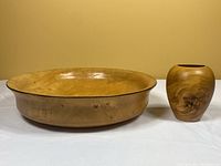 Wooden salad bowl and burl elm wood vase shown side by side on white surface, beige background.