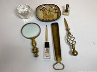 Overview of the lot showing all items arranged on flat surface: glass apple, pottery dish, magnifying glass, two letter openers, small bust statue on marble base