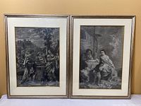 Two framed lithographs displayed side by side showing detailed grayscale scenes in 18th century style with gold trimmed frames.