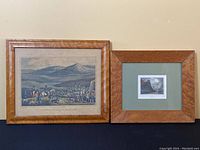 Two framed prints side by side on a black surface against a beige wall, showing both frames and visible art.