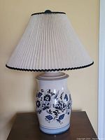 Full view of the porcelain decorative table lamp with floral motif shown with pleated fabric shade.