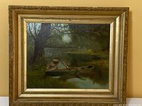 Framed oil painting depicting two canoes on a lakeshore in a natural setting with trees and water reflections