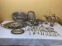 Wide view of all items on a table showing large platter, small oval tray, footed platters, pitcher, cutlery and smaller serving dishes.
