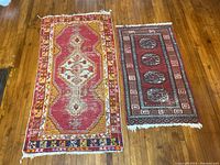 Two small area rugs side by side on hardwood floor, showing size difference and overall wear