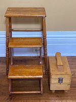 Wooden step ladder and shoe shining box side by side on wooden floor against beige wall.