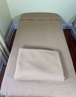 Wool blankets, one folded on top of the other on a bed showing full size and texture.