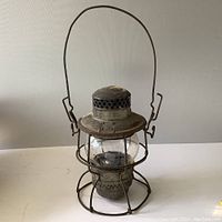 Full view of the entire lantern with handle extended, showing metal frame and clear globe.