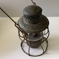 Front view of the CPR railroad lantern showing embossed 'CPR' on the top metal with wire frame and clear glass globe.