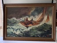 Framed oil painting showing three fishermen on a sailboat in rough sea with storm clouds