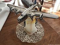 Chrome airplane atop Akro/slag glass base seen from front on wood table