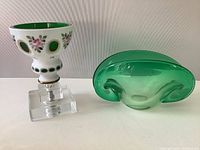 Front view of the Bohemian glass bowl on clear pedestal and modern clam shell bowl from the side
