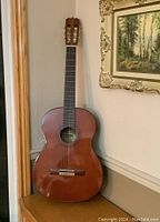 Full front view of guitar leaning against wall