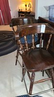 Two Ethan Allen wooden bar stools with dark finish, curved spindle backrests, solid seats, and metal footrests, next to a bar counter.