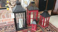 Front view of four lanterns grouped together on a patterned rug, showing their size and style differences