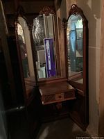 Full view of vintage wooden vanity with tri-fold mirrored panels and single drawer below center mirror.