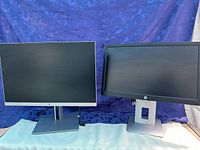 Two HP monitors side by side; left is larger 24-inch with thin bezel and silver stand, right is smaller 21-inch with thicker bezel and square base stand