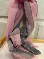 Pink and grey plaid scarf hung showing woven pattern and colors.