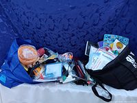 Large lot of promotional business samples and gadgets in two fabric bags on blue background