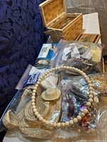 Woven basket filled with various crafting supplies including mini straw hats, beads, sequins, and plastic bags of craft materials.