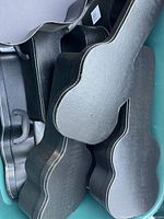 Multiple black guitar-shaped boxes stacked on each other. The boxes have separate lids and show slight dents and storage marks.