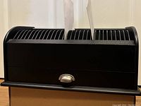 Front view of black letter sorter and organizer showing calendar day slots 1 to 31 numbered across the top and two pieces of paper inserted.