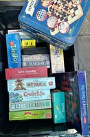 Photo of various unopened board games stacked inside a bin, showing titles and packaging.