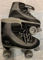 Side view of pair of Firefly Roller Derby roller skates showing black and grey high-top boot design with laces and wheels.
